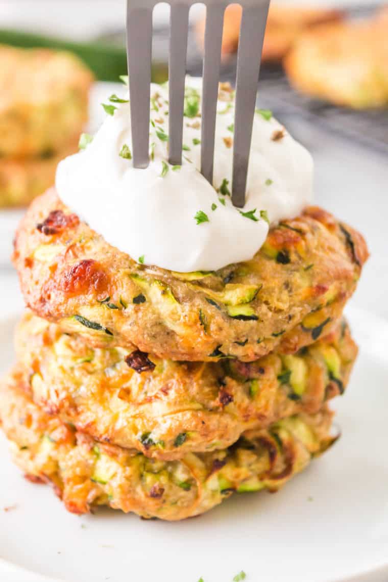 Delicious Air Fryer Zucchini Fritters, crispy and golden brown, served with a side of dipping sauce on a rustic plate.