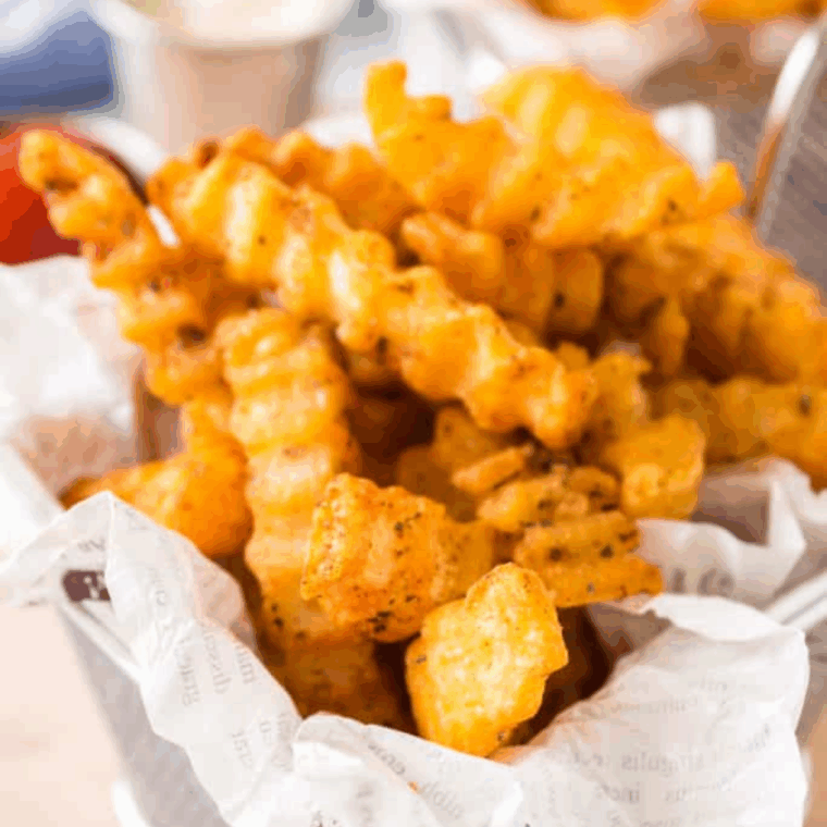 Bowl of homemade Bojangles-style French fry seasoning with golden crispy fries in the background