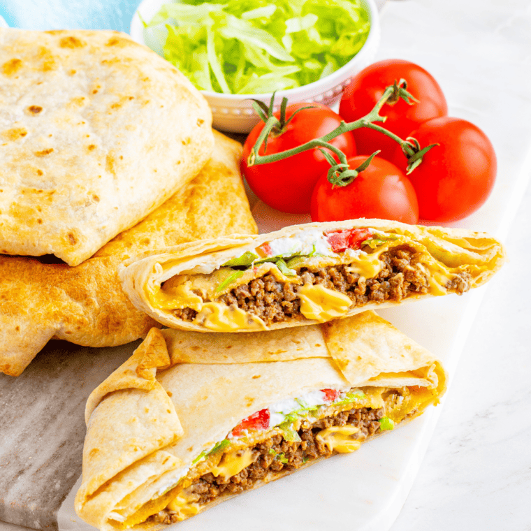 Golden brown crunchwrap supreme cooked in air fryer with visible layers of beef, cheese sauce, lettuce, and tortilla.