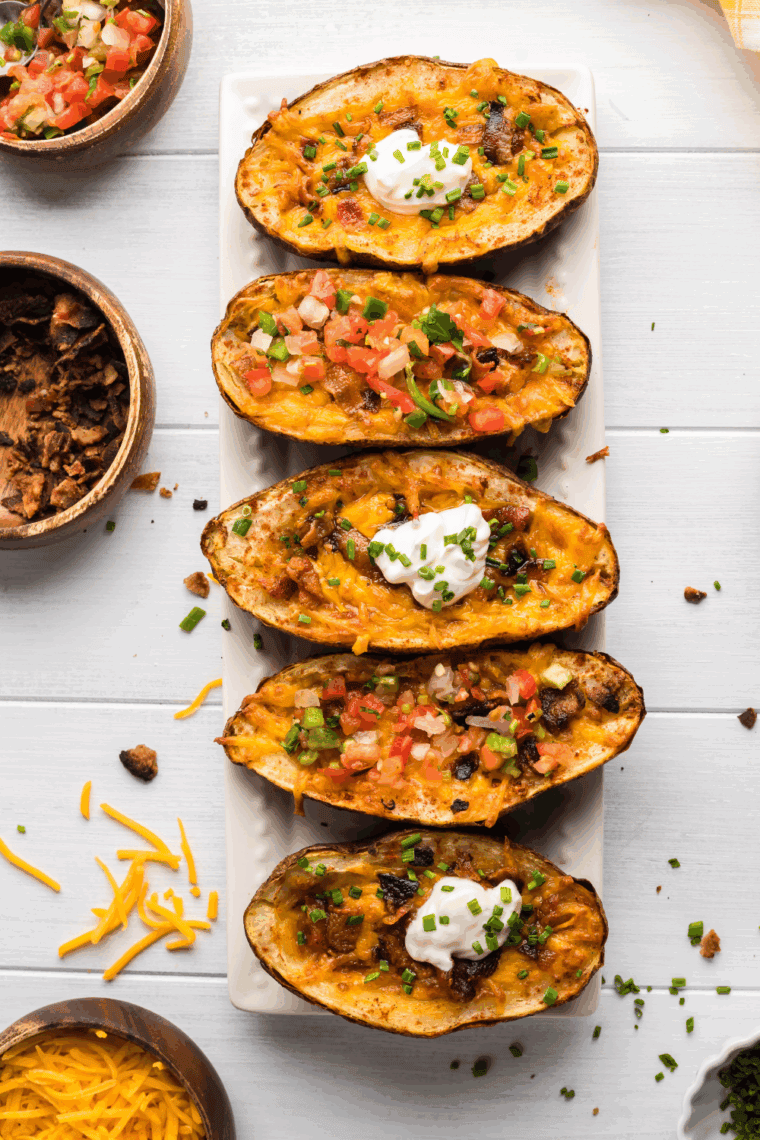 Homemade Texas Roadhouse tater skins with cheese, bacon, and green onions served on a white plate.
