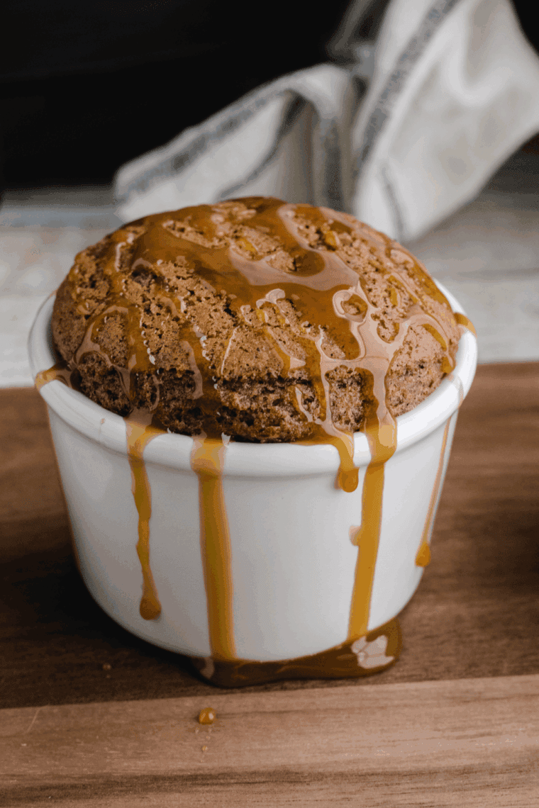Air fryer apple pie mug cake in a ceramic mug topped with cinnamon apples