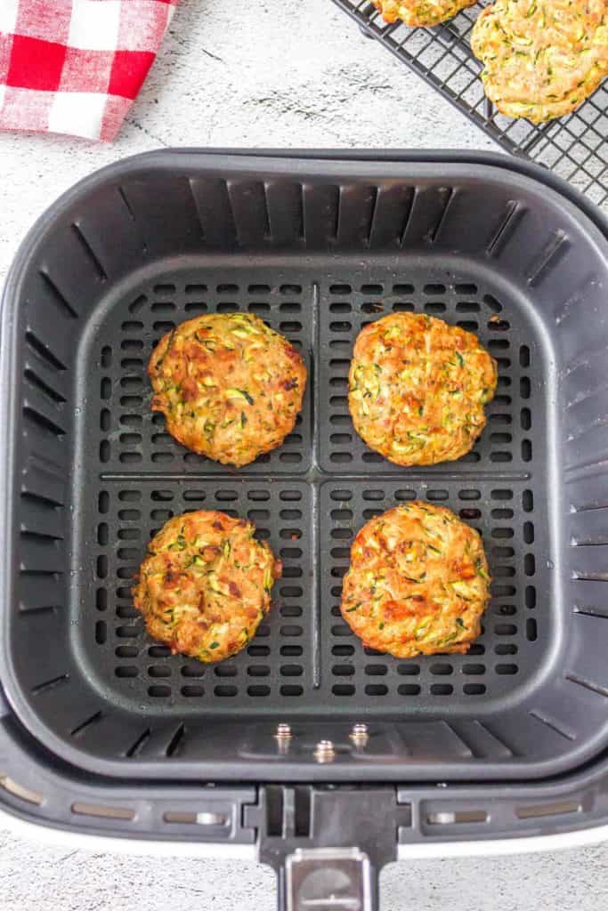 Golden brown Air Fryer Zucchini Fritters served on a plate, garnished with fresh herbs and a dipping sauce.