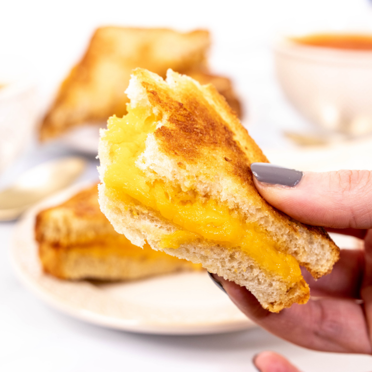 Close up of a crispy grilled cheese sandwich cooked in the Ninja Crispi with melted cheese stretching apart
