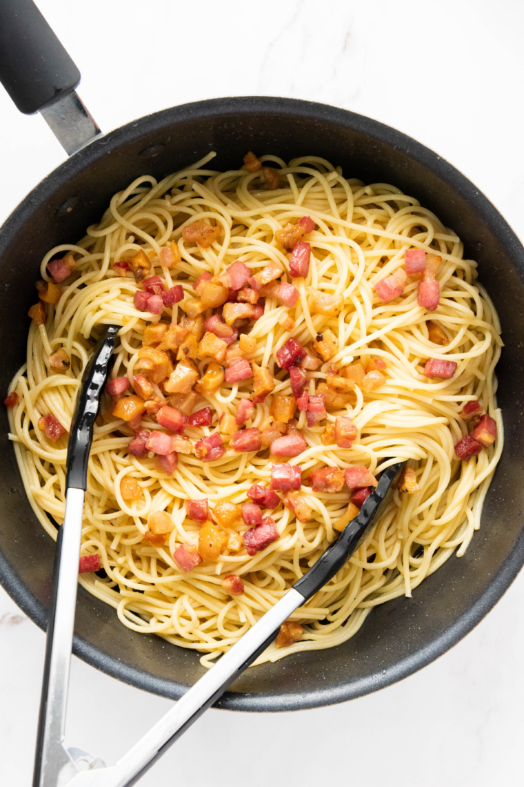 Combine pasta and bacon: Tossing hot drained spaghetti with crispy bacon and sautéed garlic in skillet