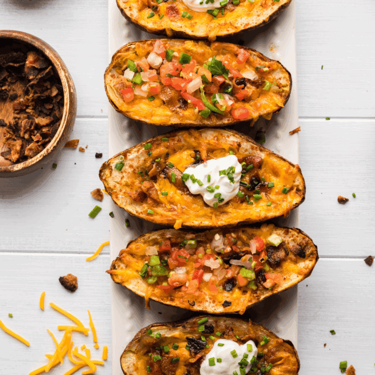 Homemade Texas Roadhouse-style tater skins topped with melted cheese, bacon, and green onions.
