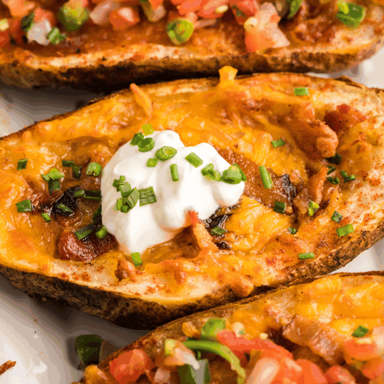 Close-up of crispy air fryer tater skins loaded with cheddar, crumbled bacon, and sliced green onions