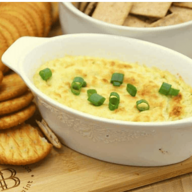 Golden-brown Air Fryer Hot Artichoke Dip garnished with parsley, ready to be served with dippers.
