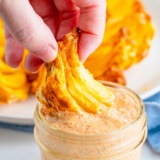 Bowl of creamy Outback bloomin' onion sauce with a crispy blooming onion petal being dipped into it