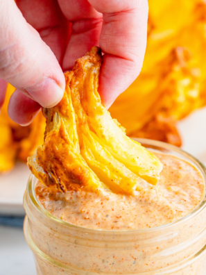 Bowl of creamy Outback bloomin' onion sauce with a crispy blooming onion petal being dipped into it