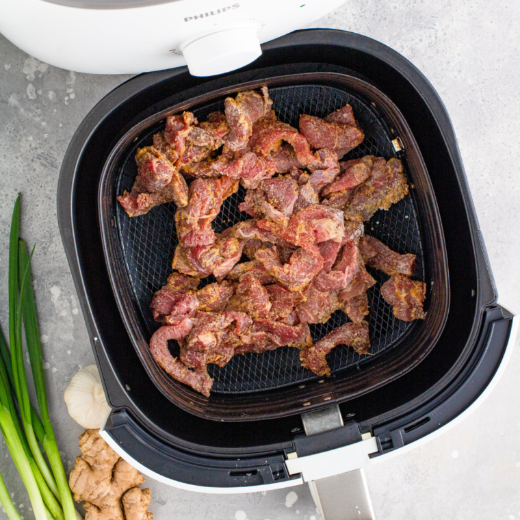 Beef slices tossed with soy sauce, garlic powder, onion powder, and cornstarch in a medium bowl, coated and ready to cook.