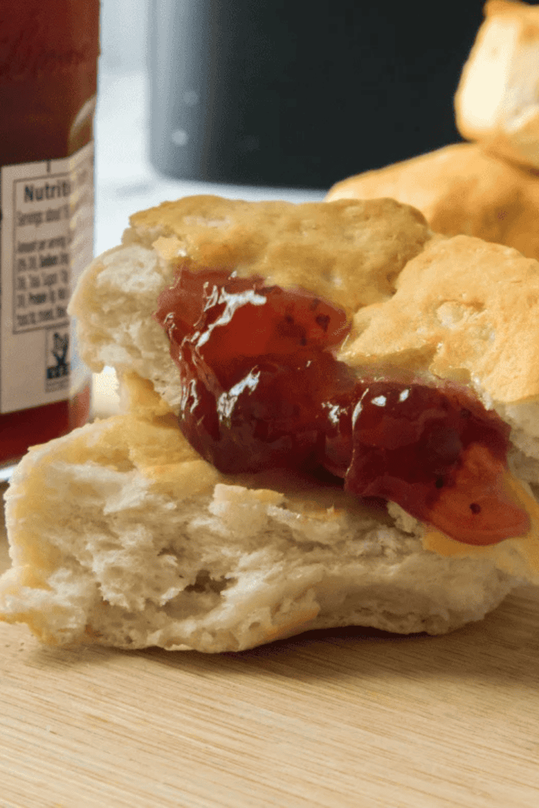 Air fryer canned biscuits cooked until golden brown and fluffy, shown in air fryer basket with soft layers inside.