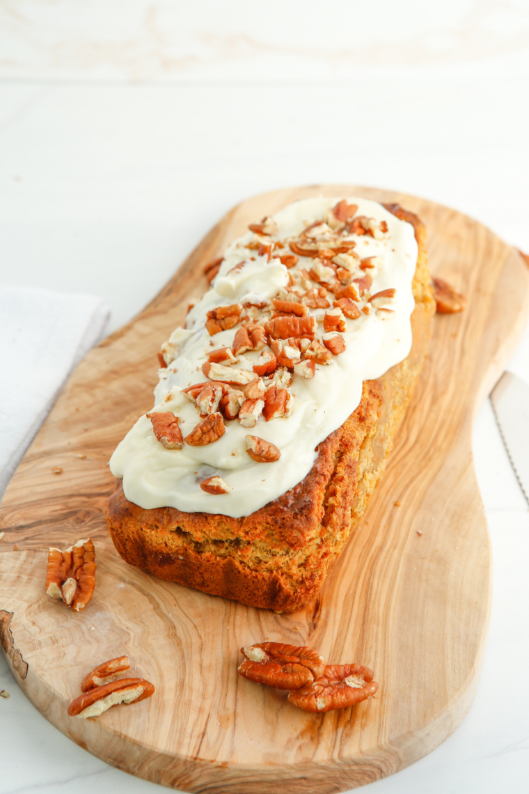 Freshly baked Air Fryer Carrot Cake Loaf with a golden-brown crust, topped with cream cheese frosting and garnished with chopped walnuts, ready to serve.