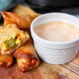 Golden brown air fryer ham and pickle egg rolls arranged on a wooden board