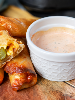 Golden brown air fryer ham and pickle egg rolls arranged on a wooden board