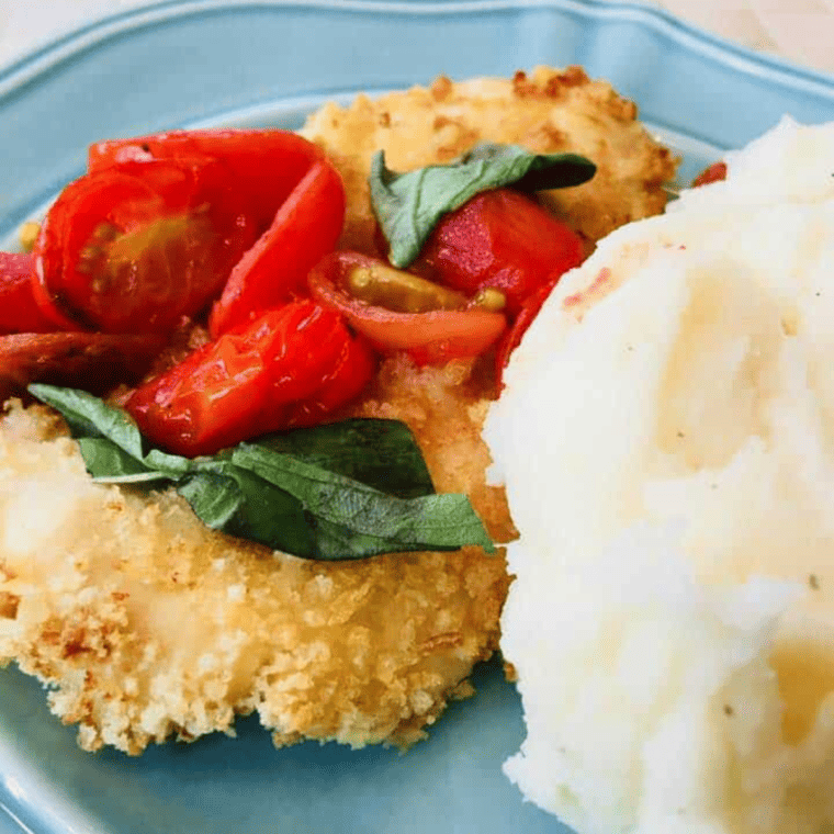 Crispy air fryer chicken Milanese topped with cherry tomato basil sauce on a white plate