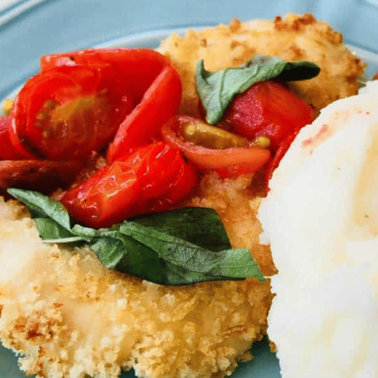 Crispy air fryer chicken Milanese topped with cherry tomato basil sauce on a white plate