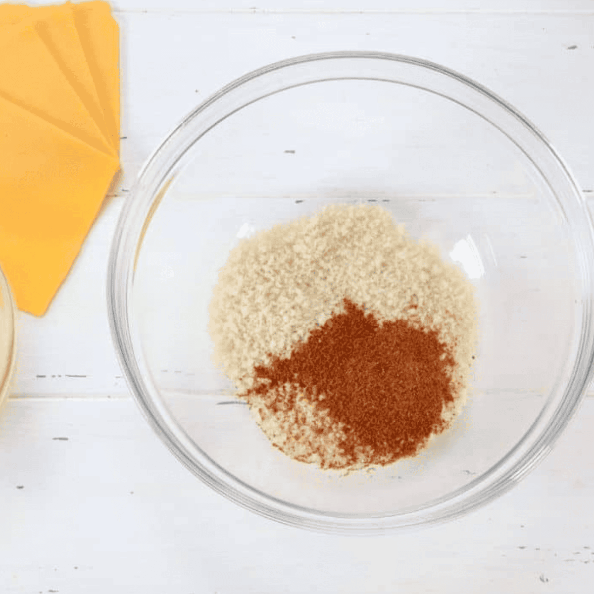 Mixing panko breadcrumbs with Old Bay Seasoning in a small bowl, and beating an egg with a fork in another bowl.