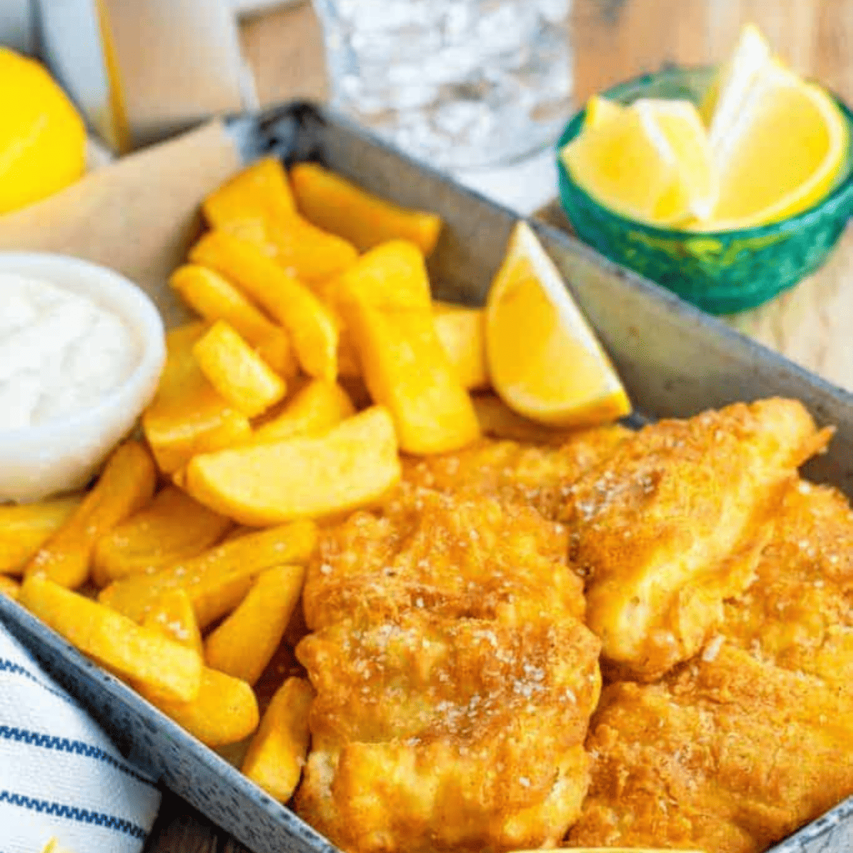 Crispy healthy fish and chips served with homemade tartar sauce on a plate.