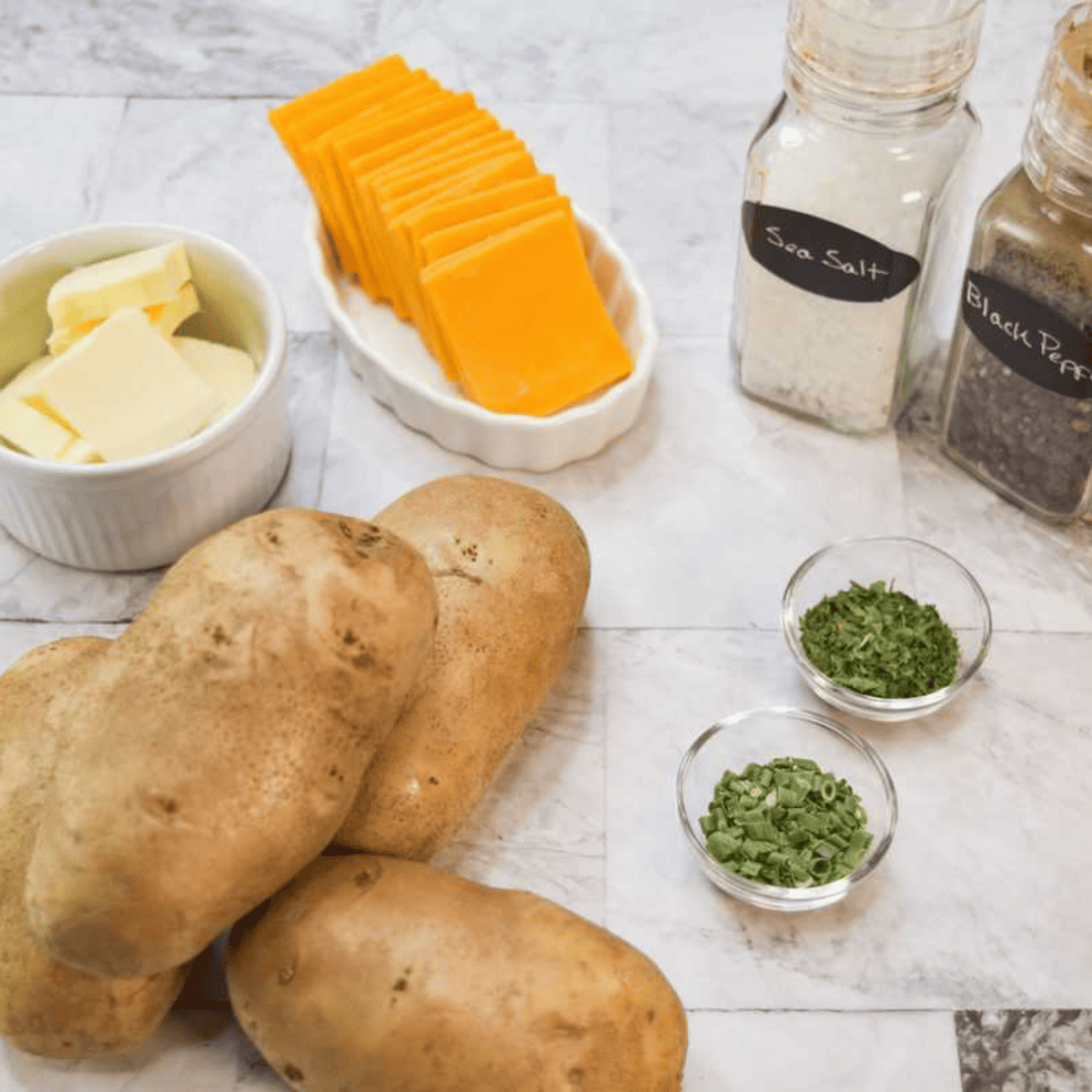 Ingredients For Air Fryer Garlic Butter Hasselback Potatoes on white marble table.