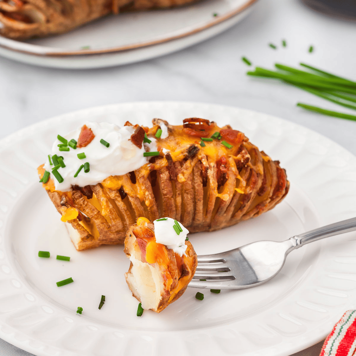 Final presentation of cooked Hasselback potatoes, garnished with fresh herbs.