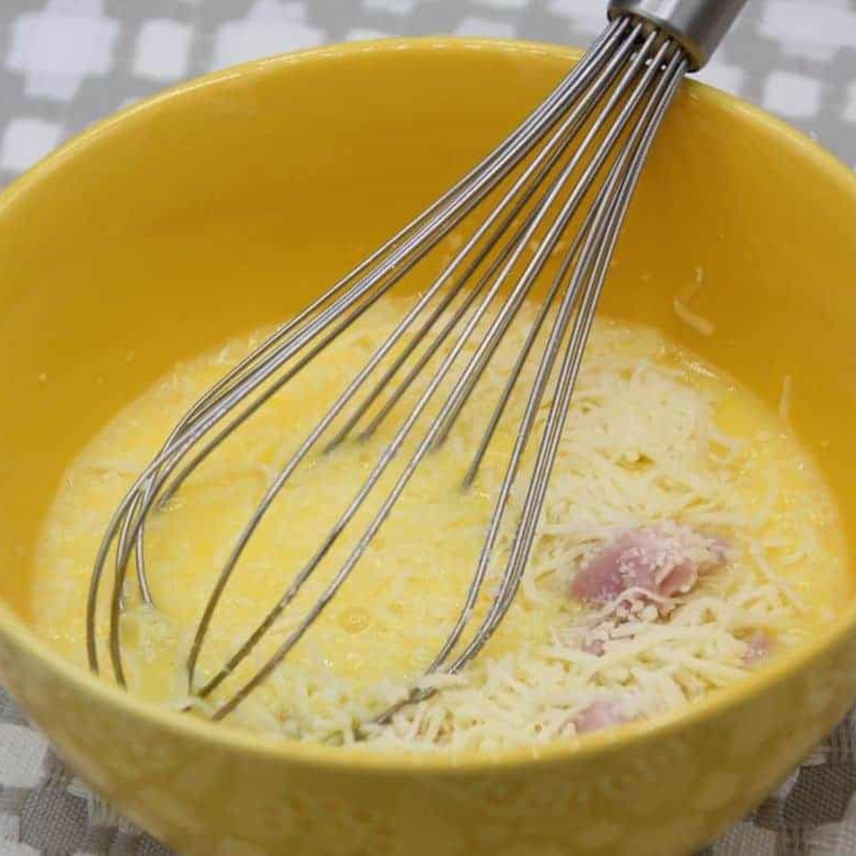 Whisked eggs, milk, salt, and pepper in a small glass bowl with visible bubbles on the frothy surface, ready for the air fryer omelette