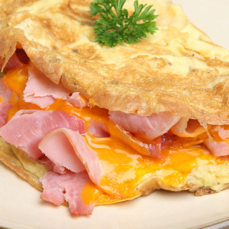 Fluffy air fryer ham and cheese omelette folded on white plate
