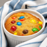Air fryer M&M mug cake in a white ramekin, topped with colorful M&M candies