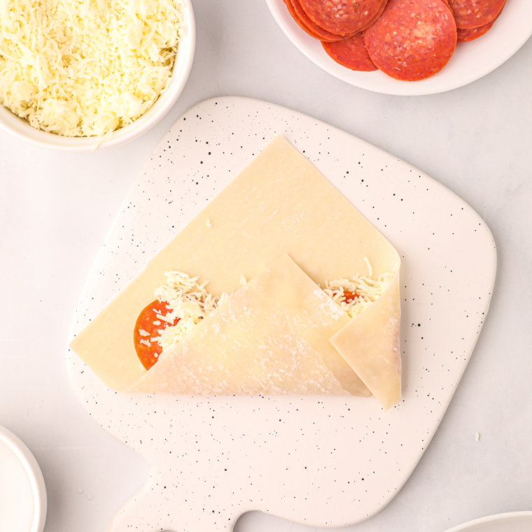 Egg roll wrapper laid flat in diamond orientation on a wooden cutting board