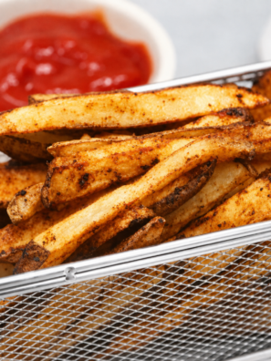Crispy air fryer spicy french fries in a white bowl with dipping sauce