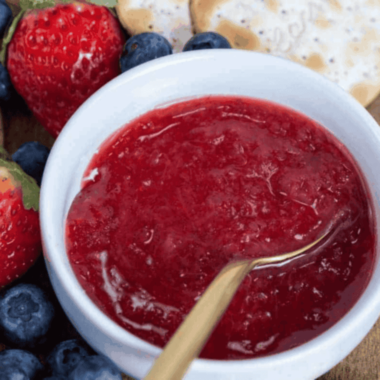 Homemade Cracker Barrel Copycat Strawberry Jam in a glass jar with fresh strawberries and spoon next to it.