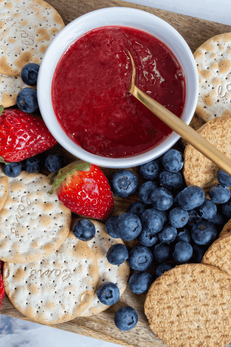 Homemade Cracker Barrel Copycat Strawberry Jam in a glass jar with fresh strawberries on the side.