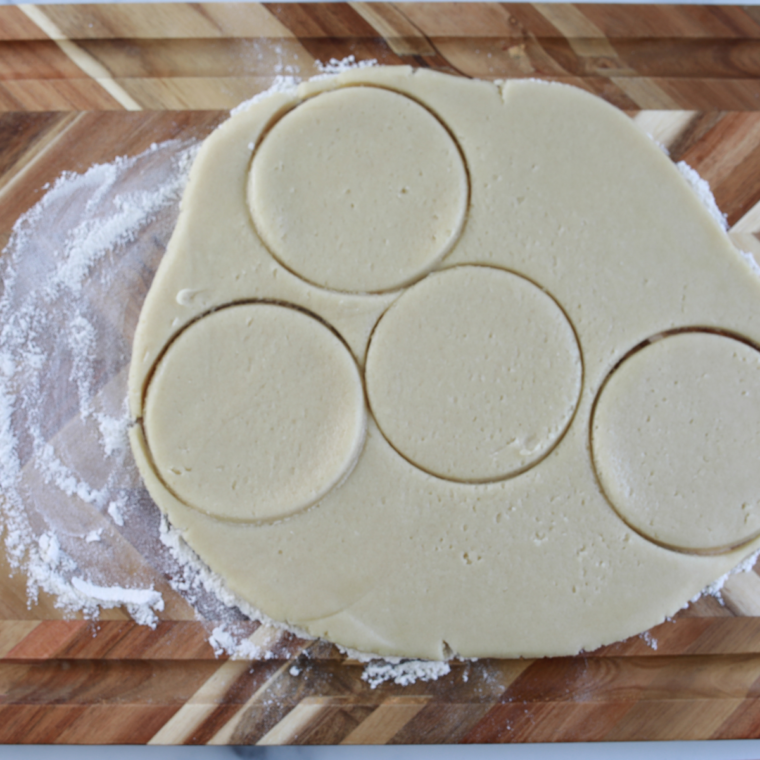 Cutting cookie dough circles with a biscuit cutter slightly larger than a muffin tin.