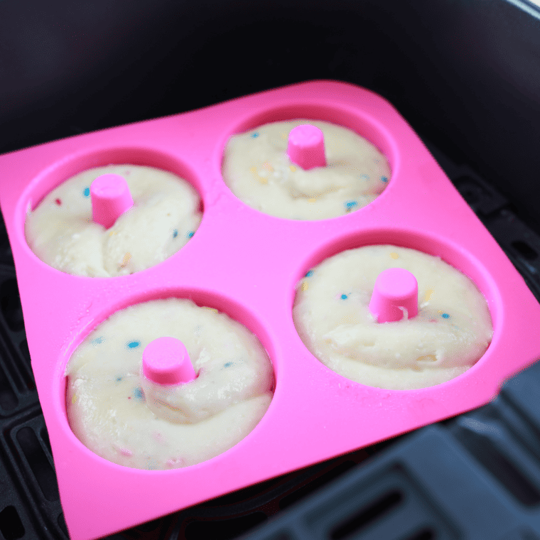 Piping Funfetti batter into a silicone air fryer donut pan