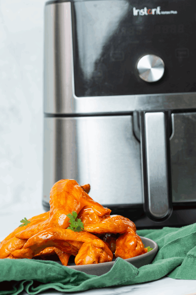 Close-up of crispy air-fried buffalo wings with celery sticks and blue cheese dip.