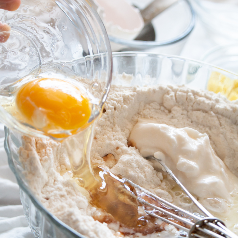 Mixing egg, sugar, vanilla, milk, yogurt, oil, lemon juice, and zest into donut batter