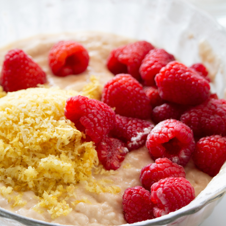 Folding fresh raspberries into donut batter in a mixing bowl