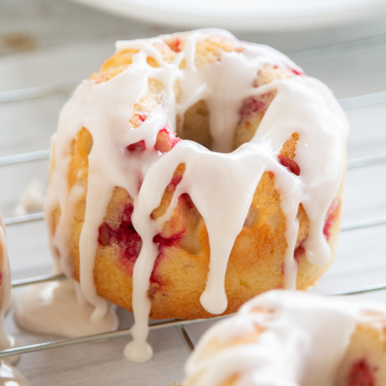 Drizzling lemon glaze over cooled raspberry lemon donuts