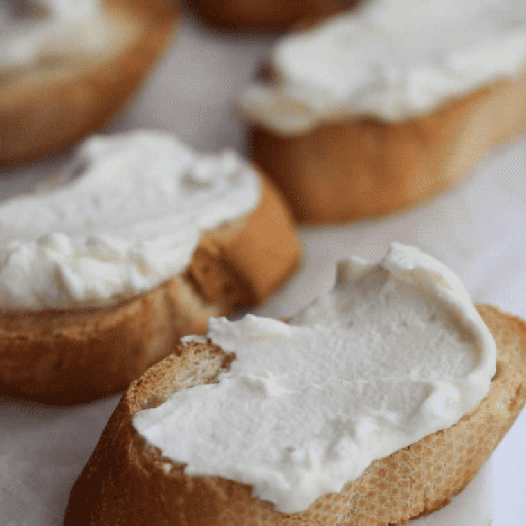 Mascarpone spread on a toasted crostini and topped with neatly arranged sliced strawberries