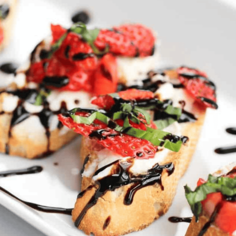 Strawberry bruschetta variation drizzled with balsamic glaze and garnished with fresh basil