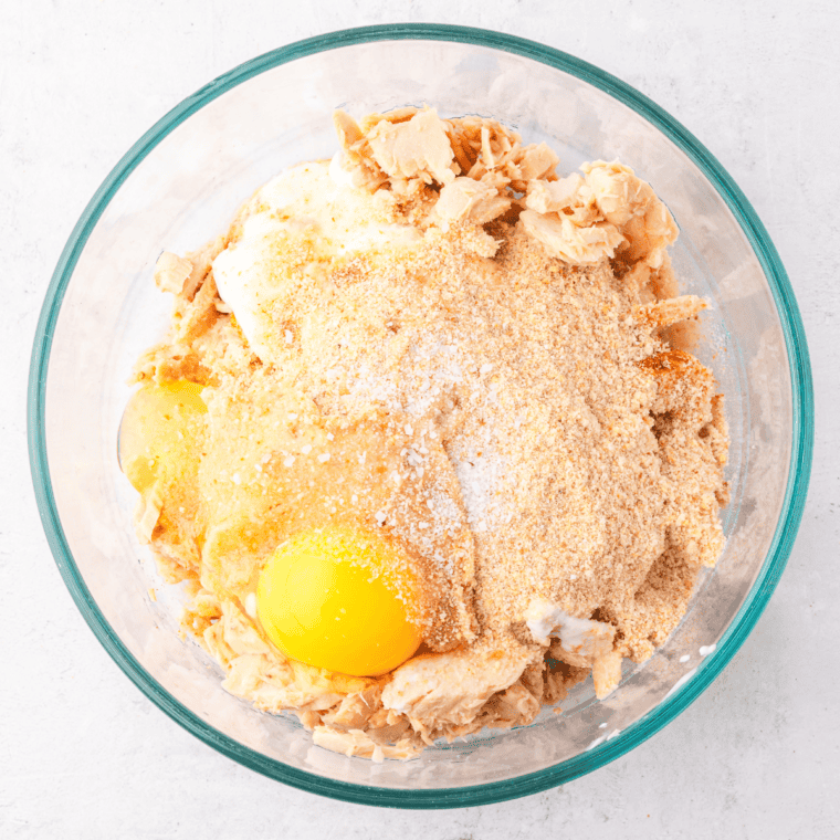 Ingredients for salmon patties in a bowl, including canned salmon, breadcrumbs, mayonnaise, egg, lemon juice, Dijon mustard, and seasonings, mixed together until well combined.