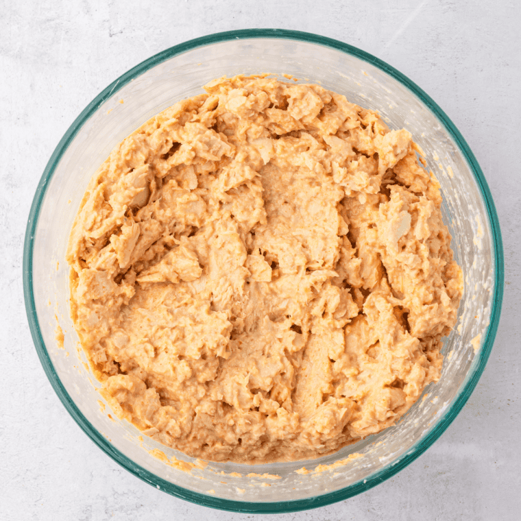 Salmon patty mixture being stirred together in a bowl, with breadcrumbs added to achieve the right consistency.