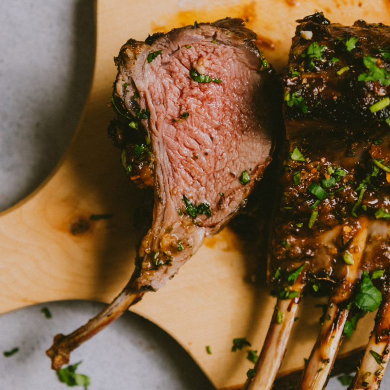 Plated lamb chops garnished with fresh herbs and lemon wedges, ready to eat with a rich, glossy finish.
