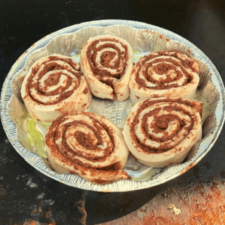 Cinnamon rolls browning on a Blackstone flat-top griddle before flipping