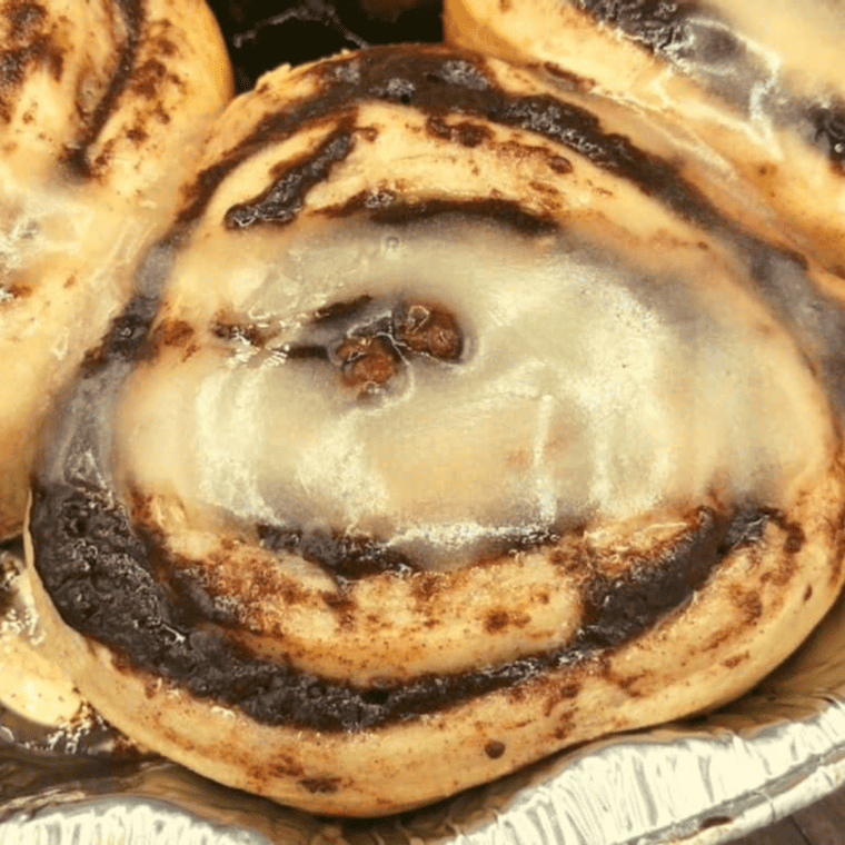Golden brown cooked cinnamon rolls on the Blackstone griddle ready for icing.