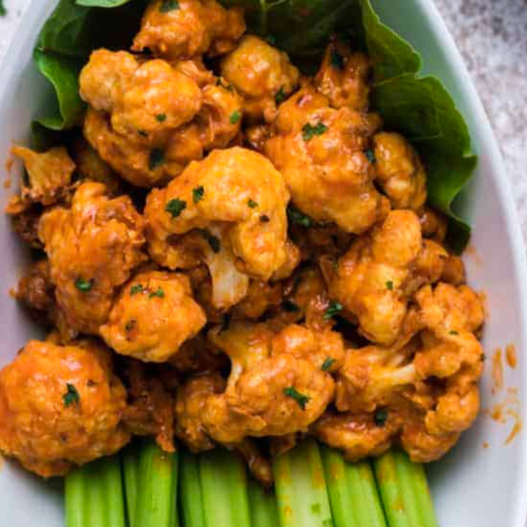 Air fryer cooking frozen buffalo cauliflower until crispy and golden.