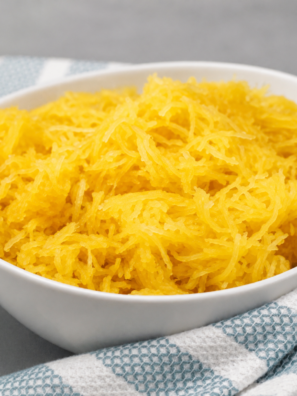 Shredded Ninja Foodi spaghetti squash strands in a white bowl with a fork