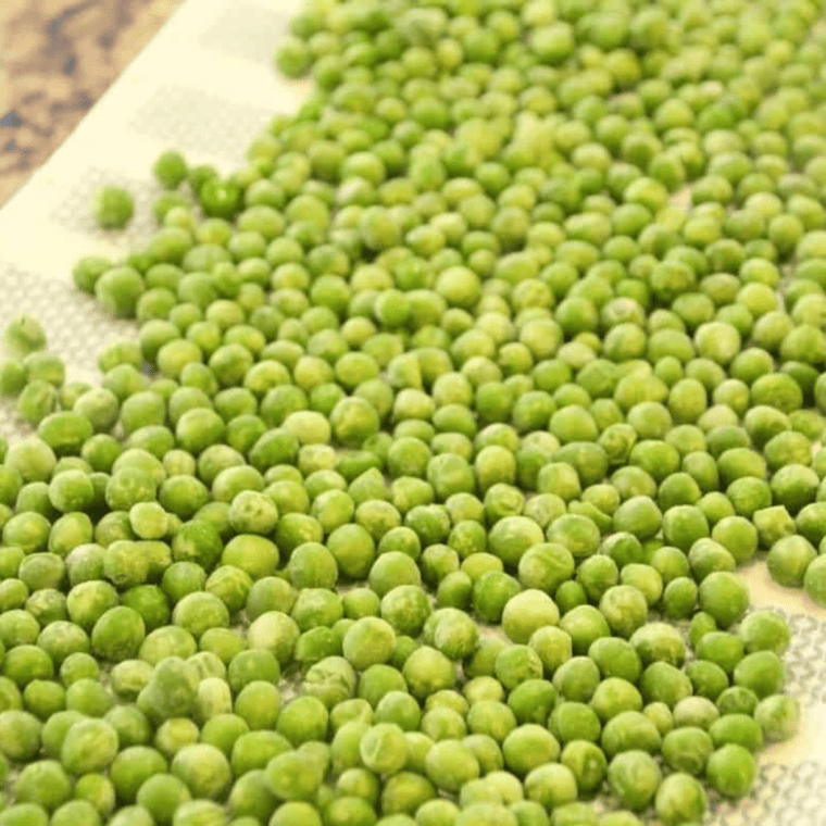 Frozen peas laid out on a kitchen towel to dry for 10-15 minutes.