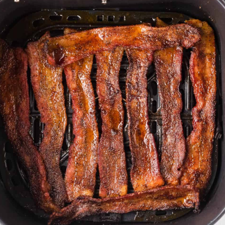 Seasoned bacon strips arranged in a single layer in the air fryer