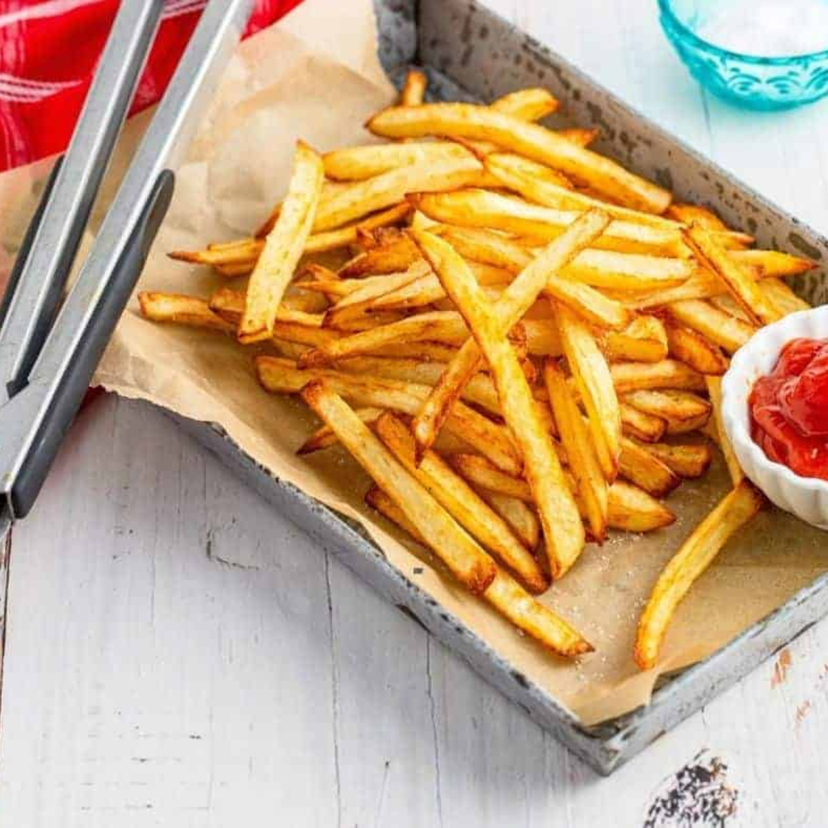 Golden brown, thin French fries piled high in a red carton, resembling copycat McDonald's fries made in an air fryer.