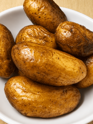 Crispy air fryer fingerling potatoes on a white plate with blistered skins and flecks of kosher salt